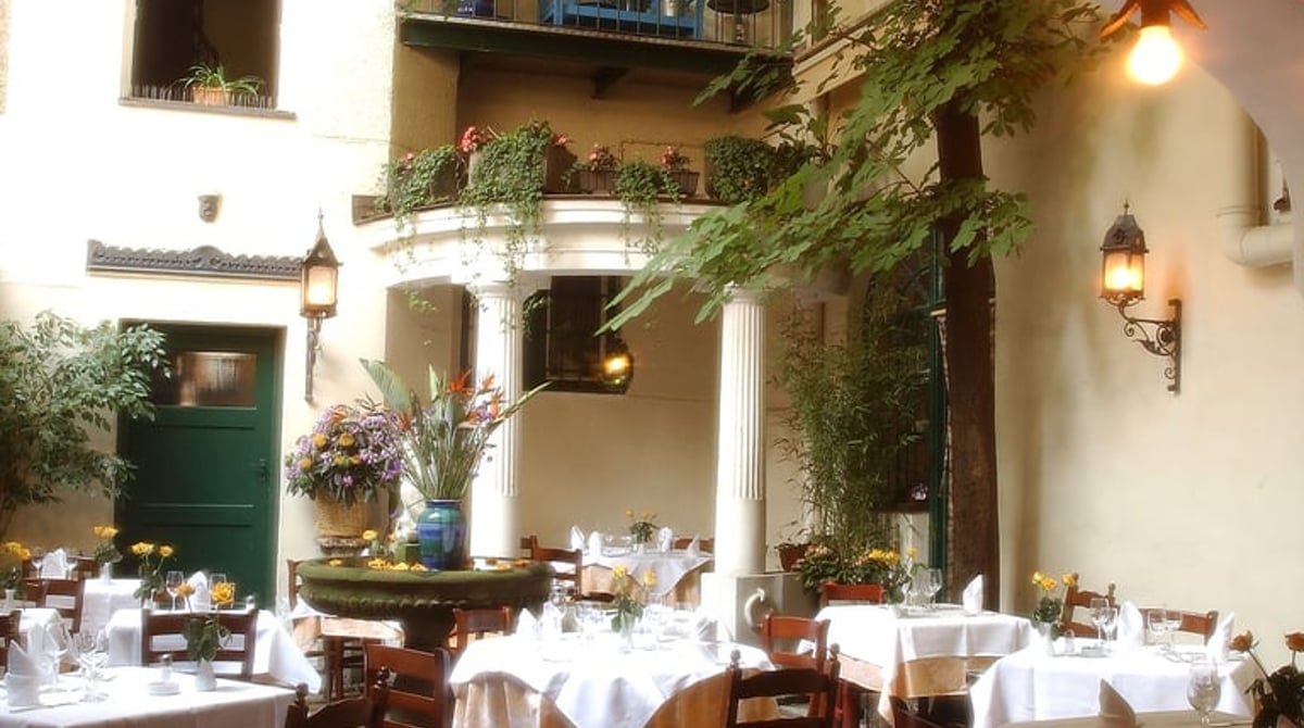 Terrasse im Innenhof der Osteria Italiana mit eingedeckten Tischen unter Arkaden