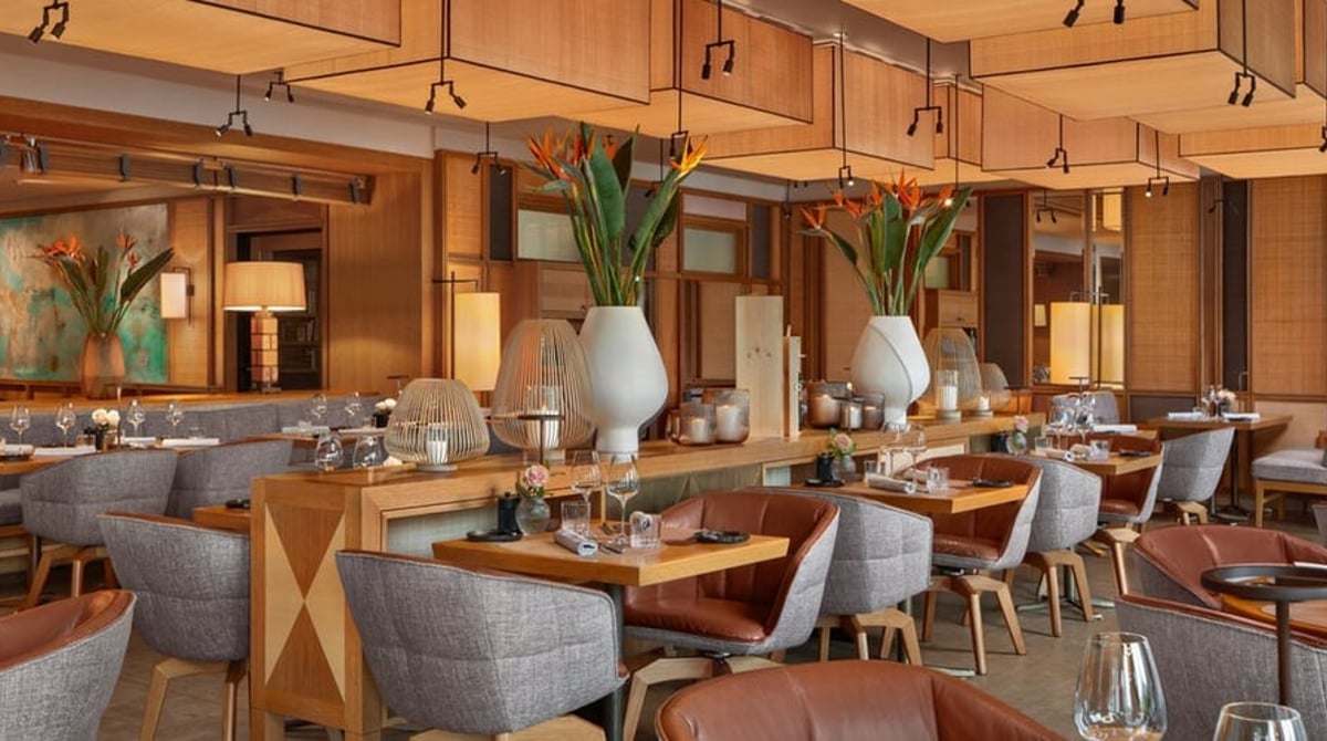 Restaurant im LOUIS Hotel München mit Holztischen, Sesseln und warmem Licht