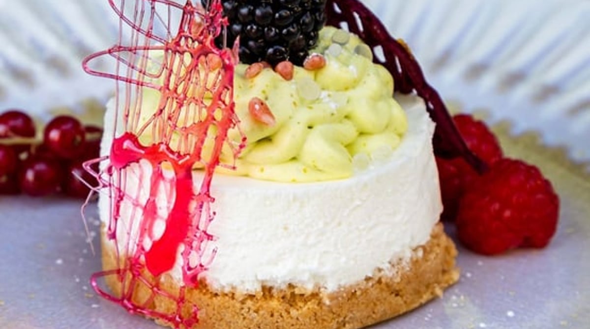 Pistazien-Käsekuchen mit Waldbeeren auf einem blauen Teller