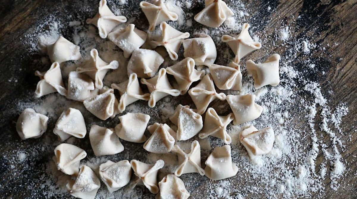 Frisch geformte Manti auf einer bemehlten Holzfläche