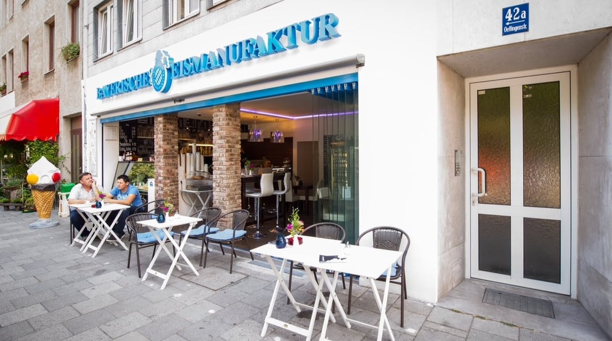 Außenansicht der Bayerischen Eismanufaktur an der Oettingenstraße mit Markise und Tischen vor dem Haus