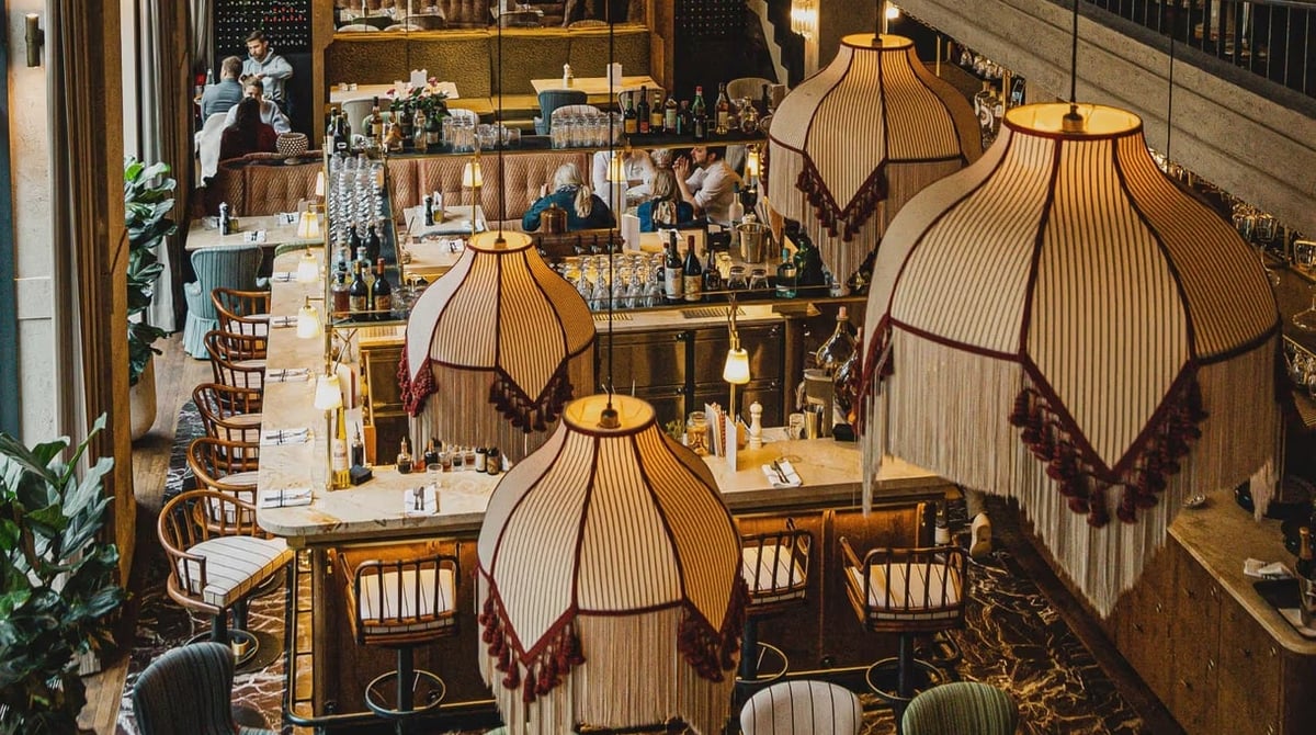 Blick von oben auf die Bar der Gigi Trattoria mit Fransenlampen und Barhockern