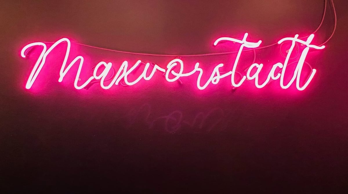 Pinkfarbener Neon-Schriftzug „Maxvorstadt“ an der Wand der Hamburgerei