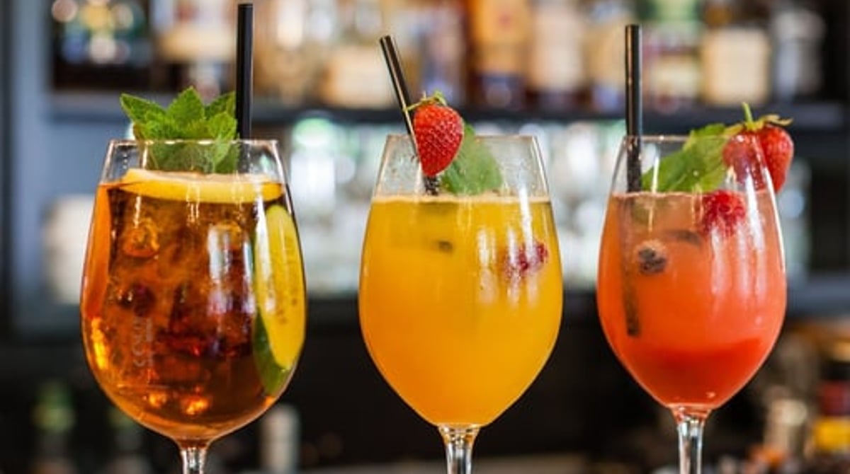 Drei Cocktails vor dem Flaschenregal der Bar