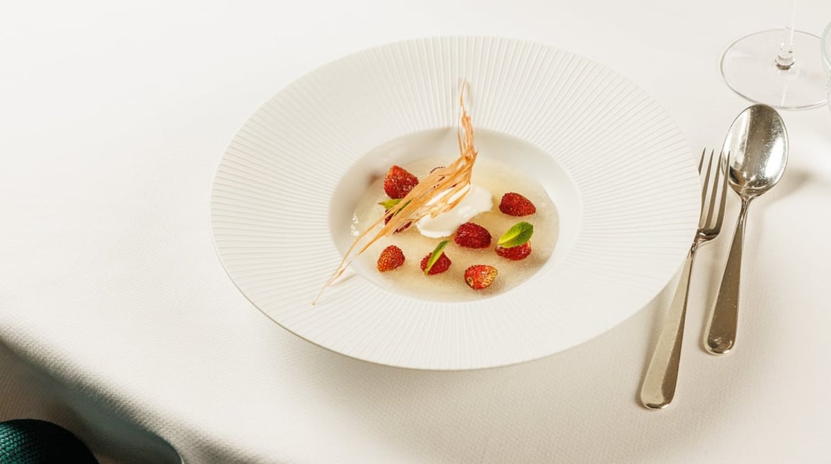 Dessert mit Erdbeeren in klarer Brühe auf einem tiefen Teller