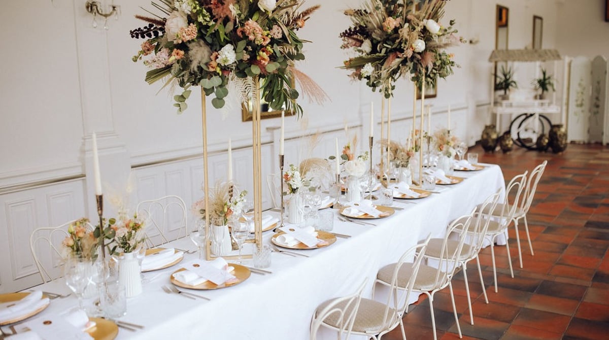 Gedeckter Tisch mit Trockenblumen im hellen Saal des Palmenhauses