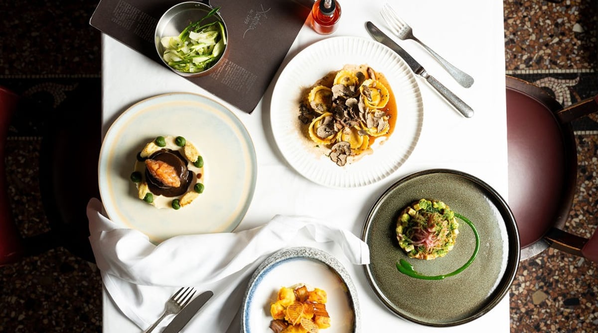 Gedeckter Tisch mit vier Tellern: Pasta, Fleisch, Gemüse und Kartoffeln