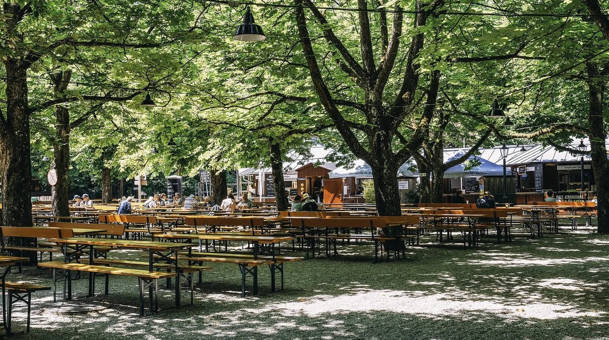 Bierbänke unter hohen Kastanien im Biergarten Waldheim in München-Großhadern