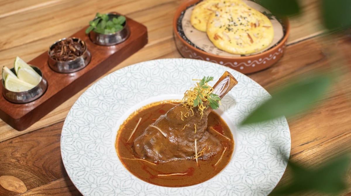Lamb Shank Nihari: geschmorte Lammhaxe in dunkler Sauce, dazu Brot und Beilagen