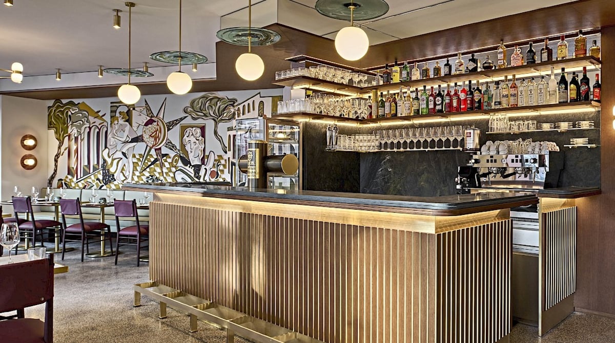 Bar mit Flaschenregal und Gastraum mit Pendelleuchten