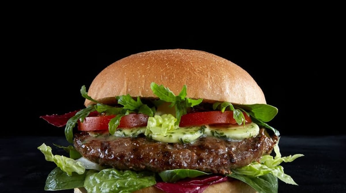 Burger mit Rindfleisch-Patty, Kräutercreme, Tomate und Salat im hellen Brötchen