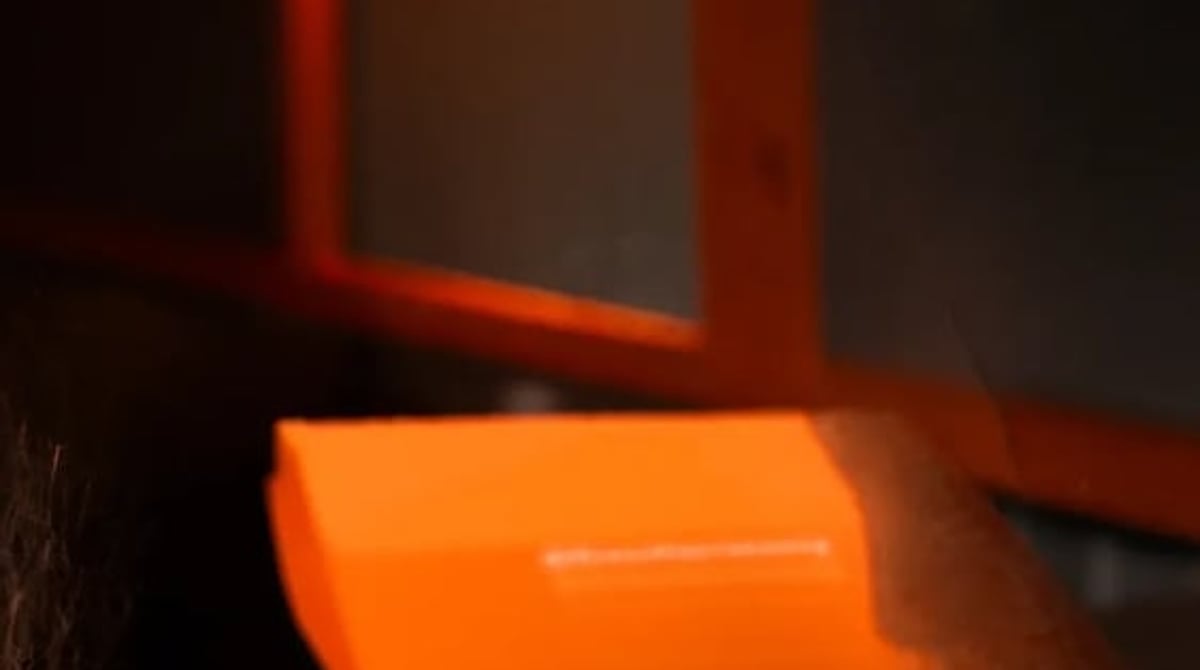 Orange Shawarmery-Box auf einem Tisch, dahinter ein leuchtender Neon-Schriftzug im Laden