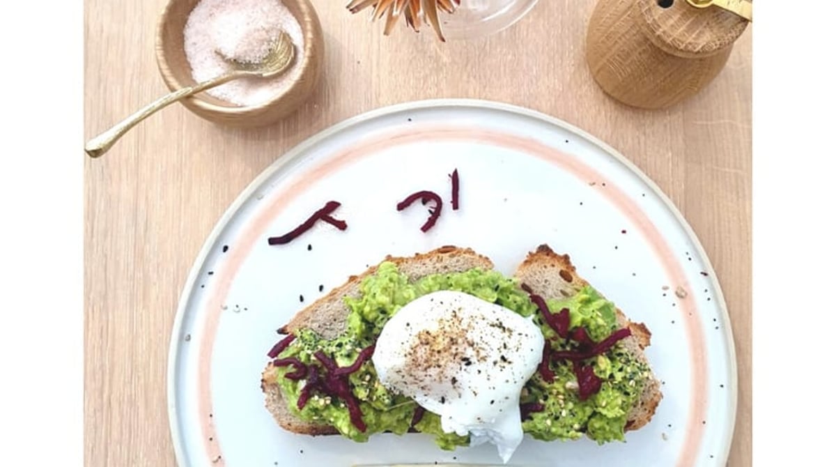 Sauerteigbrot mit Avocado und pochiertem Ei auf einem Teller mit rosa Rand