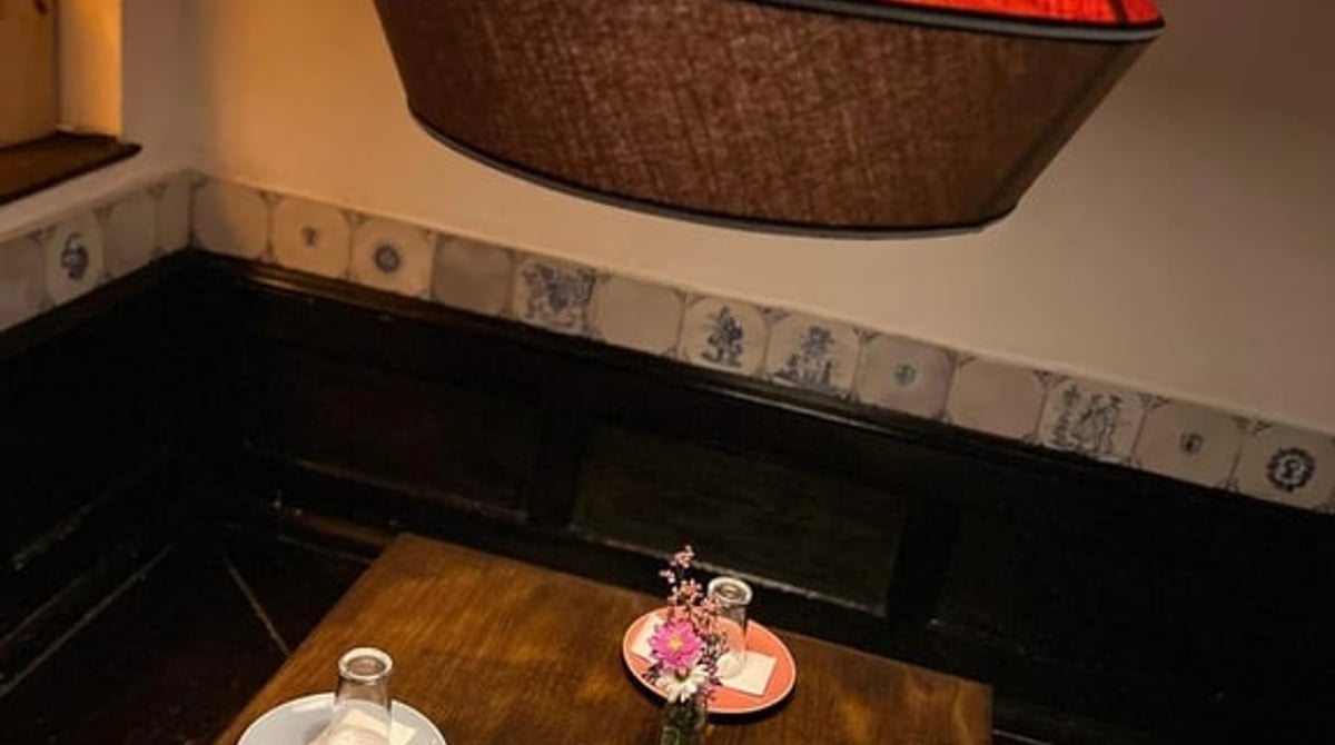 Holztisch mit bunten Tellern unter einer roten Lampe in der Bodega Dali
