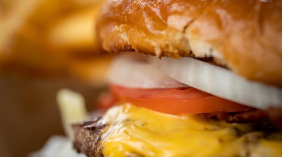 Cheeseburger mit Tomate, Zwiebel und Salat in Nahaufnahme