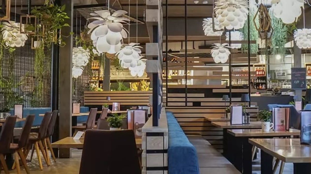 Heller Gastraum des Kiefl Café & Restaurant in Gauting mit hängenden Lampen, Holztischen und blauer Sitzbank