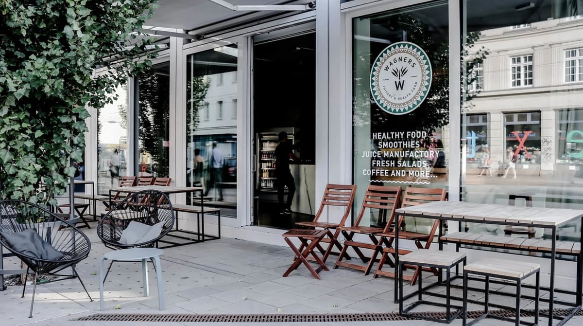 Tische und Stühle vor dem Eingang von Wagners Juicery an der Fraunhoferstraße