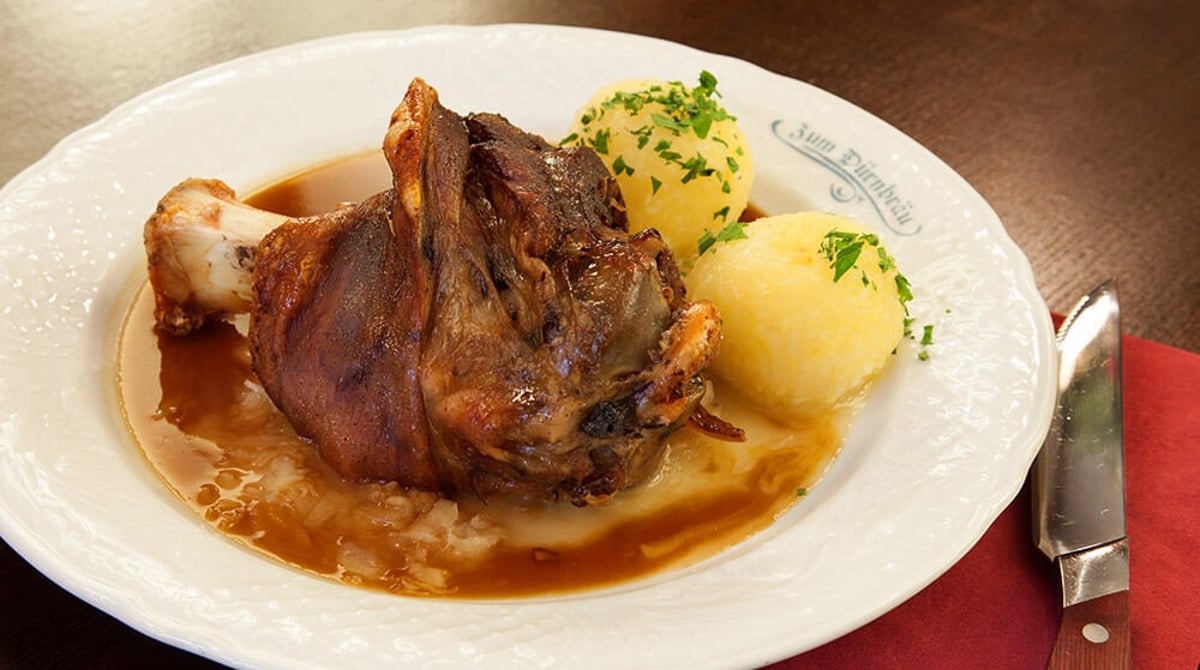 Schweinshaxe mit Knödeln und Soße auf einem Teller mit Dürnbräu-Schriftzug