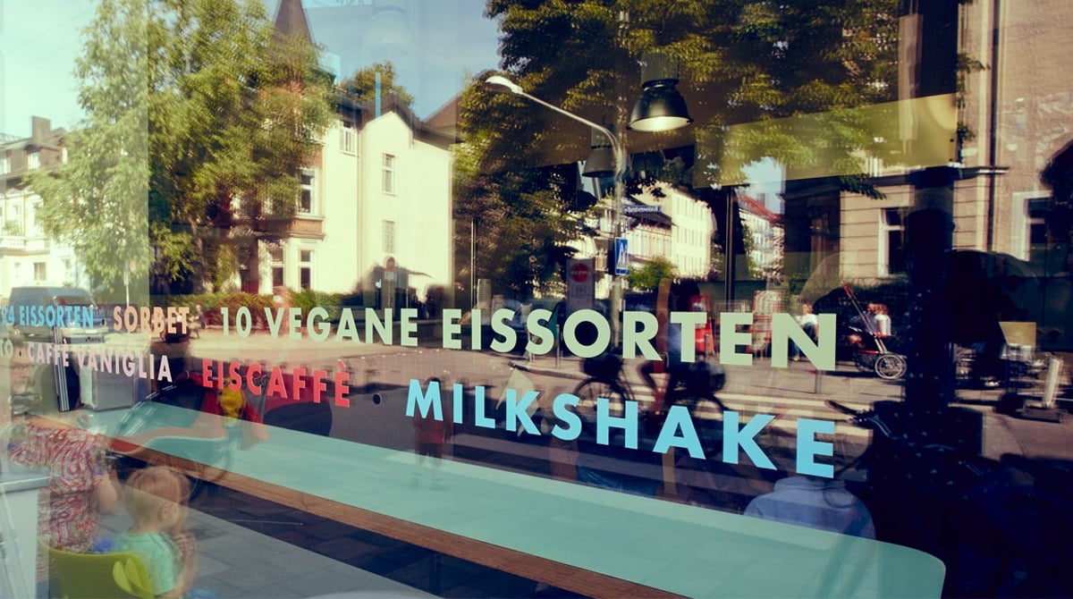 Schaufenster der Eismanufaktur mit Schriftzug „10 vegane Eissorten“, Eiscaffè und Milkshake