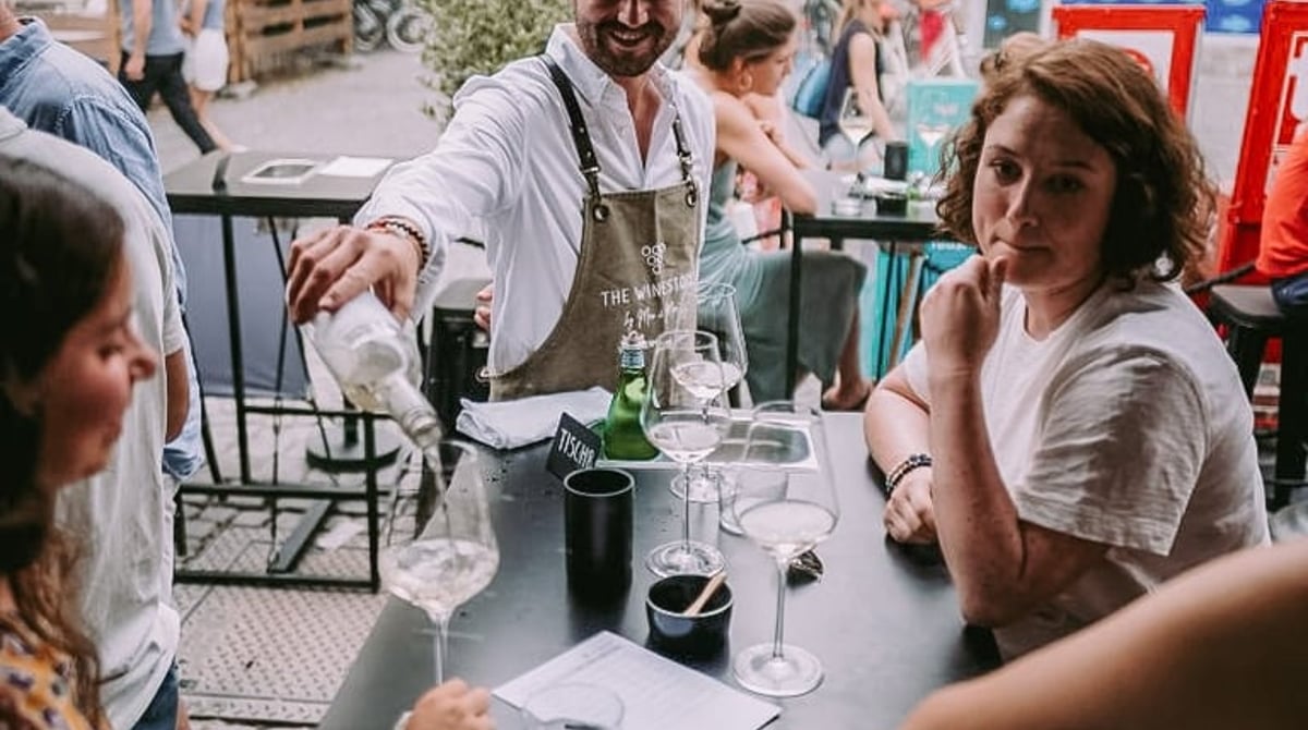 Der Kellner schenkt Gästen an einem Tisch im Freien Wein ein