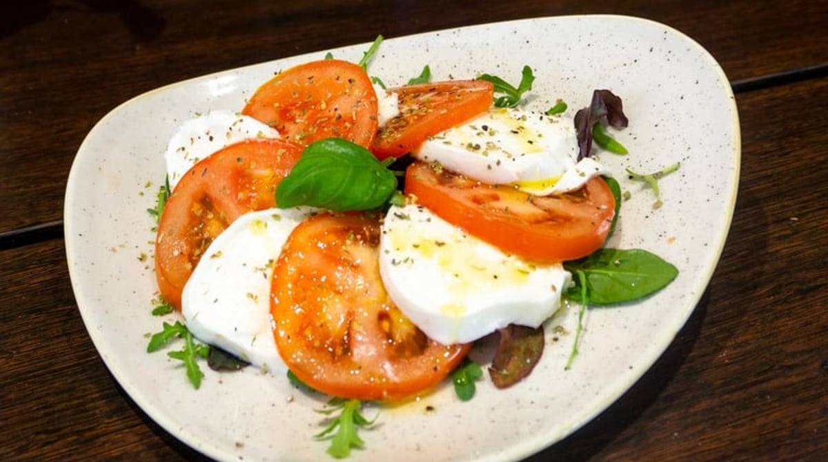 Caprese mit Tomaten, Mozzarella und Rucola auf einem Teller