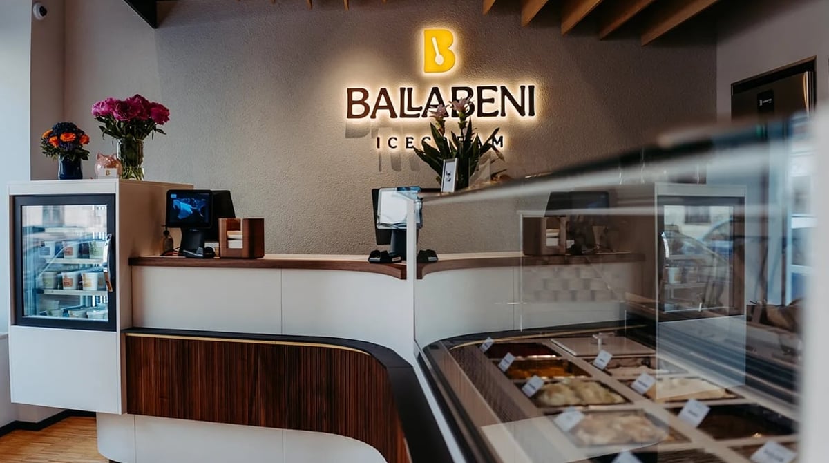 Eistheke von Ballabeni Icecream mit beleuchtetem Logo an der Wand und gefüllter Vitrine