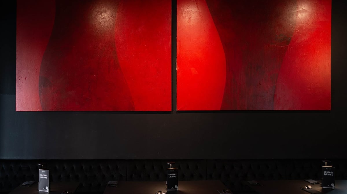Schwarz gehaltener Gastraum des PARK Korean Eatery mit eingedeckten Tischen und roten Gemälden an der Wand