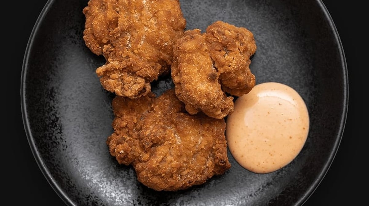 Frittierte Hähnchenstücke mit Sauce auf schwarzem Teller