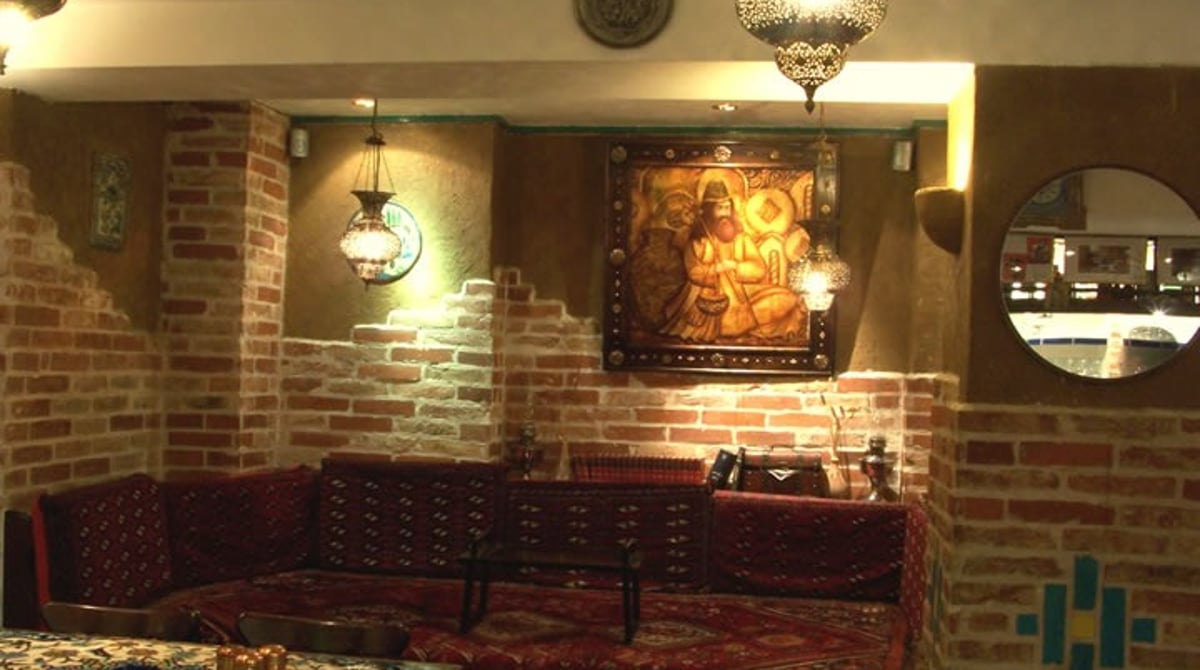Sitzecke mit Teppichen und Kissen vor einem Wandbild im pars