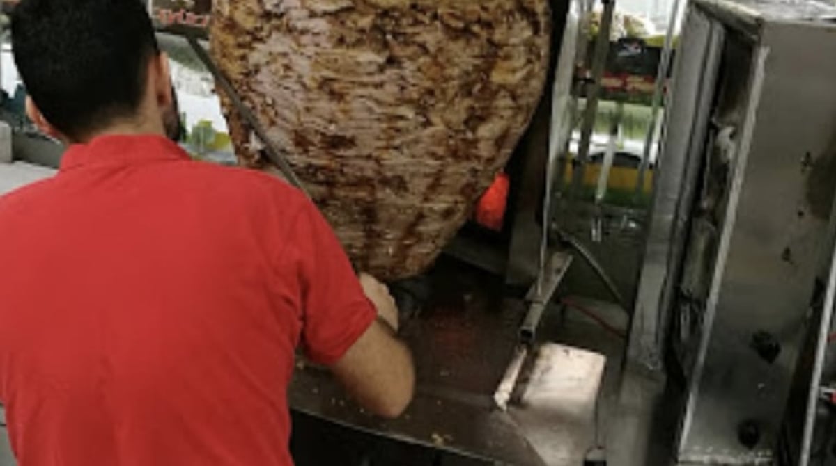 Dönerspieß an der Theke des Verdi Süpermarkts, davor ein Mitarbeiter