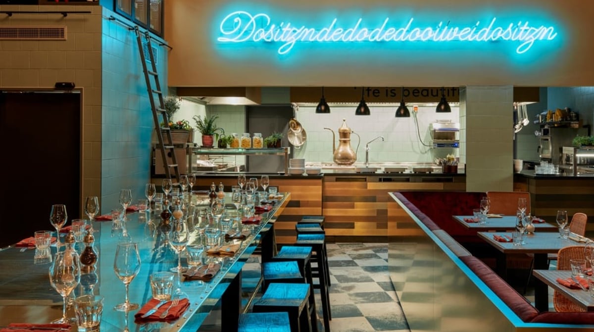Langer Tisch, Bar und offene Küche im Gastraum des NENI München