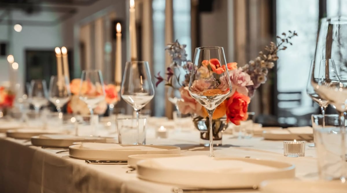 Festlich gedeckte Tafel mit Blumen und Kerzen vor den Fenstern des Y.OUR Pavillons