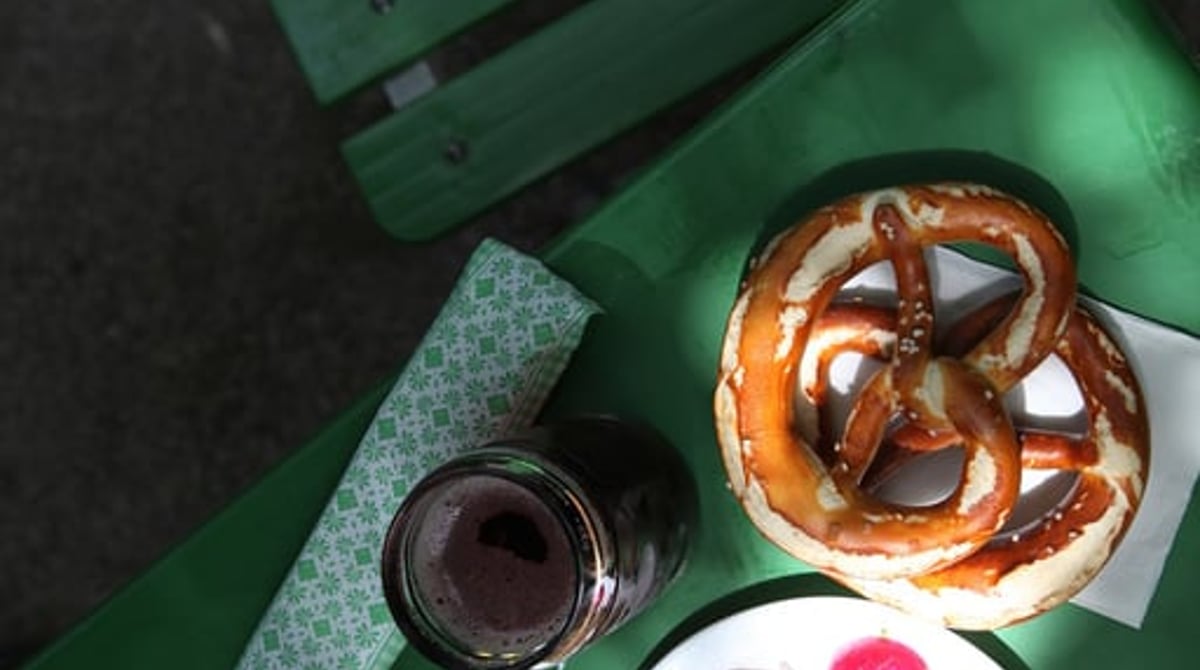 Brotzeit mit Brezn, Obazda und Radieserl auf einem grünen Biergartentisch