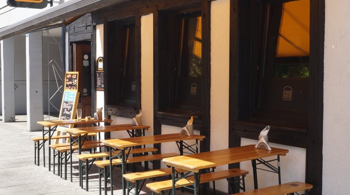 Außenansicht des Burger House an der Theresienstraße mit Bierbänken und Tischen auf dem Gehweg
