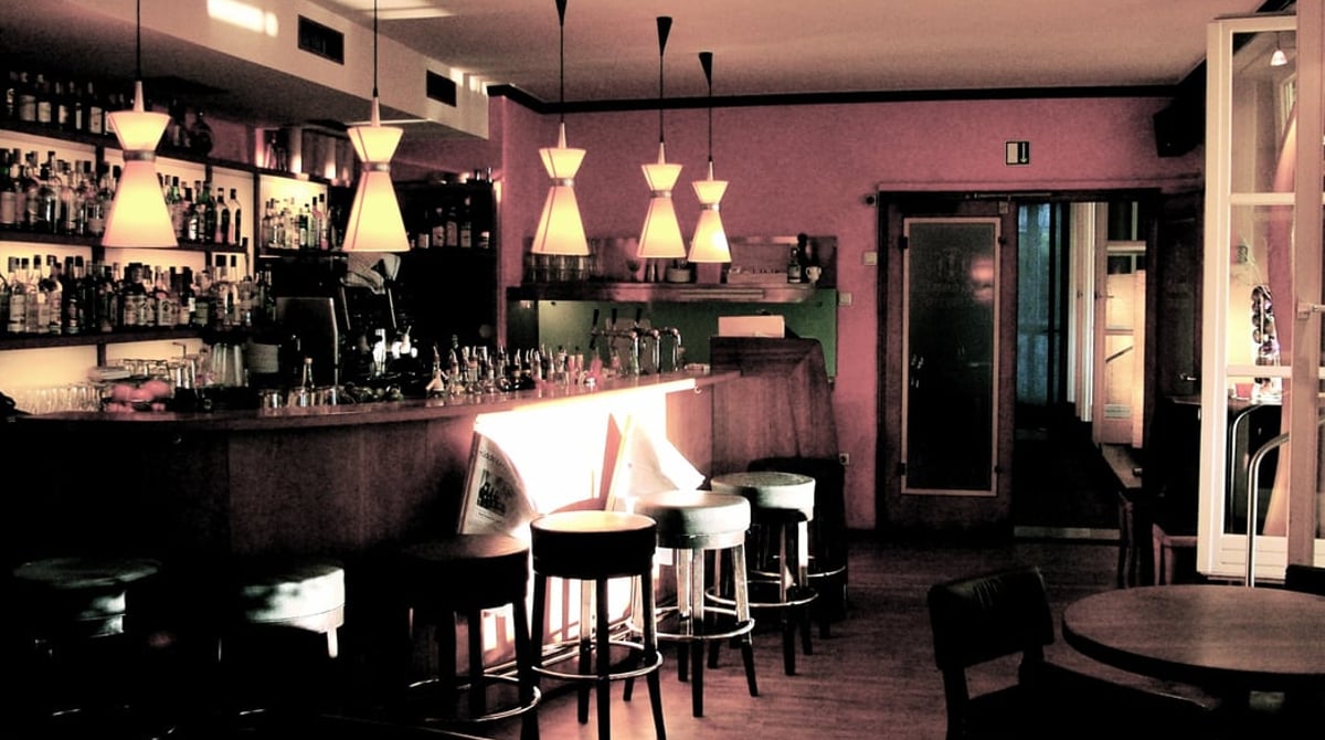 Bar mit Barhockern, Flaschenregal und Pendelleuchten im Cafe Glockenspiel