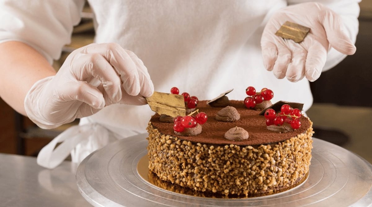 Eine Konditorin verziert eine Schokoladentorte mit Johannisbeeren