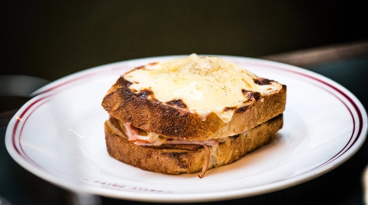 Croque Monsieur mit gratiniertem Käse auf einem Teller mit rotem Rand
