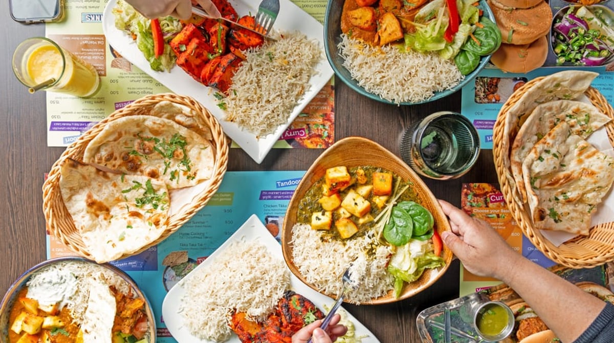 Tisch mit Currys, Naan, Tandoori-Hähnchen und Reis von oben fotografiert