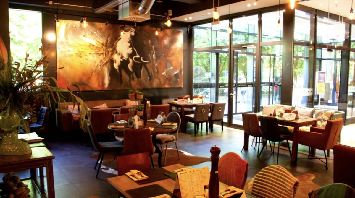 Gastraum der Churrascaria mit großem Stier-Gemälde, Holztischen, Polsterstühlen und Glasfront
