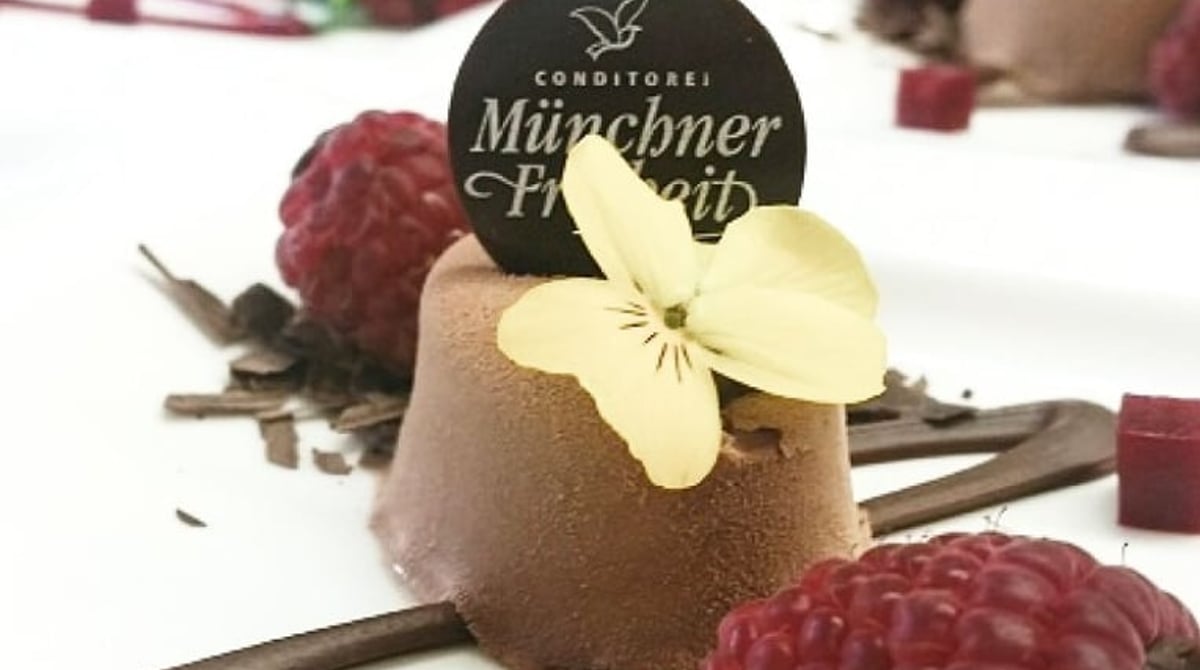 Törtchen mit Himbeeren und Schokoladenschild der Konditorei Münchner Freiheit