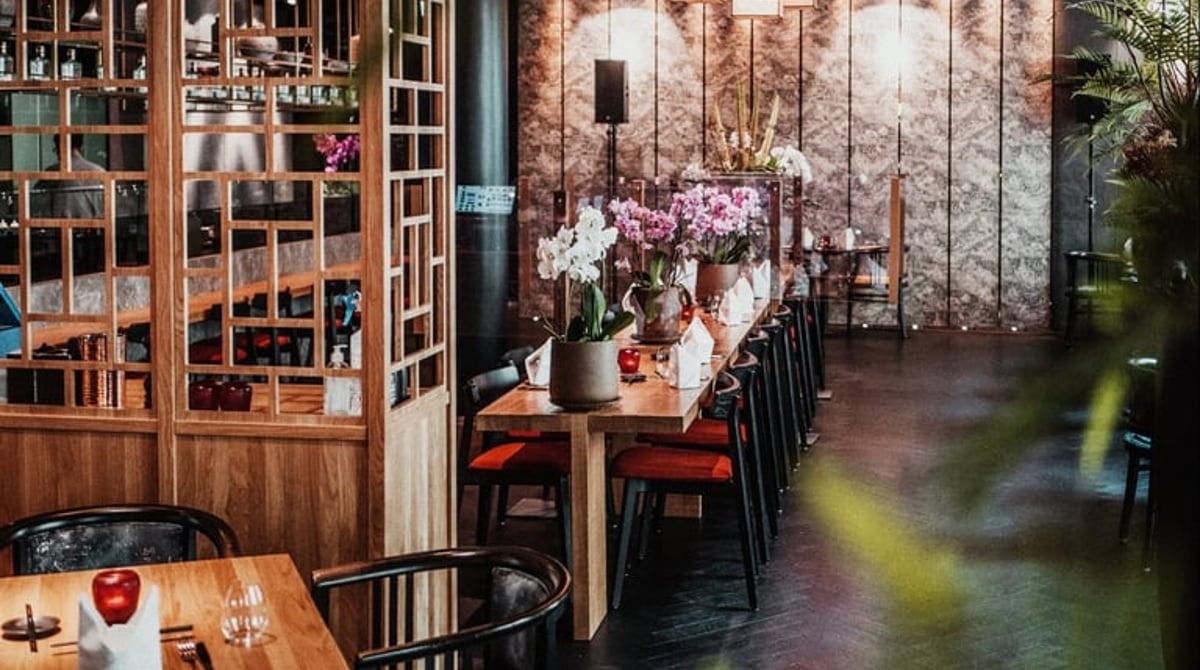 Holzraumteiler, gedeckte Tische und Blumenschmuck im Restaurant Azuki