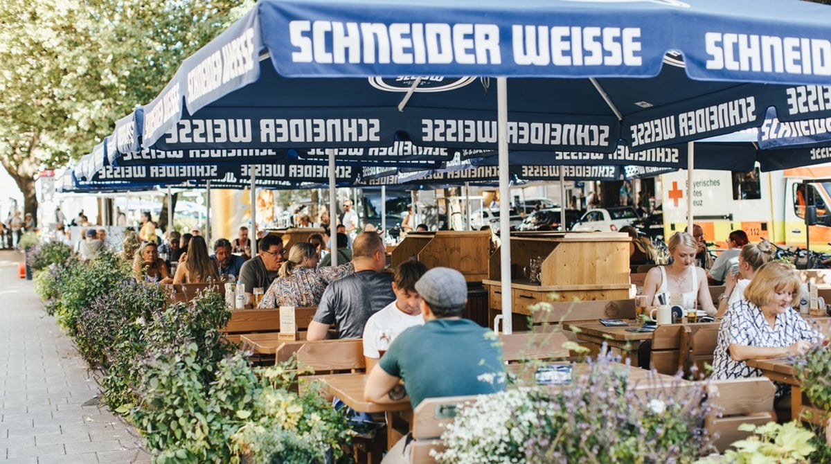 Terrasse vor dem Weissen Bräuhaus mit blauen Schneider-Weisse-Sonnenschirmen