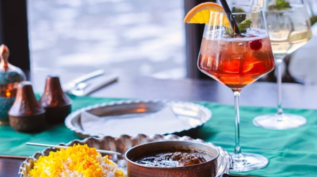 Fensterplatz mit Cocktail, Safranreis und Schmorgericht auf dem Tisch im Diwan