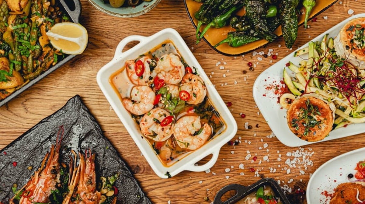 Tapas-Tisch von oben mit Oliven, Pimientos de Padrón, Garnelen und weiteren Tellern