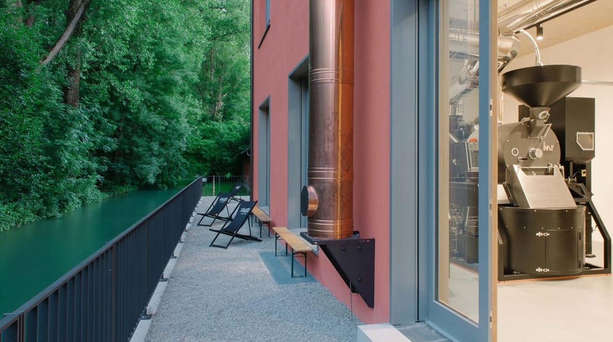 Gläserne Rösterei in der Kraemer'schen Kunstmühle: Röstmaschine hinter der Glasfront, links der Auer Mühlbach