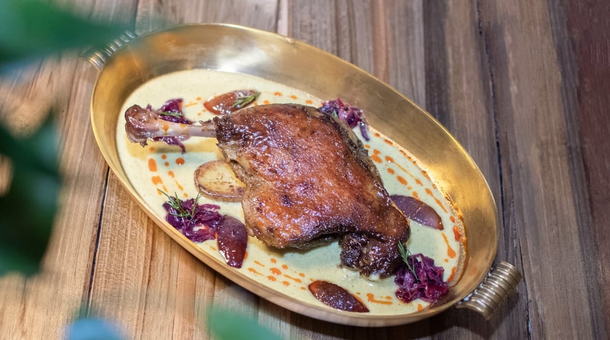 Knusprige Entenkeule auf Sauce in einer goldenen Schale
