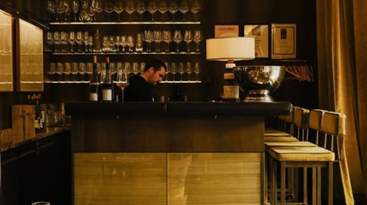 Gastraum der GRAPES Weinbar mit Bar, Holztischen und Fischgrätparkett