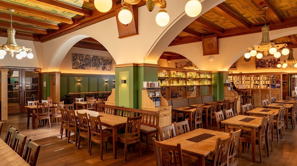 Lokal des Hofbräukellers mit Holztischen, Rundbögen und Empore
