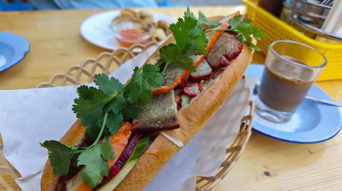 Banh Mi, ein belegtes vietnamesisches Baguette mit Fleisch, Gurke, Möhren und Koriander, im Korb auf einem Tisch