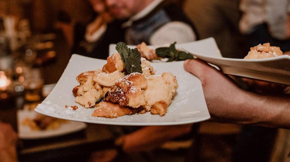 Kaiserschmarrn auf einem Teller, der am Tisch serviert wird